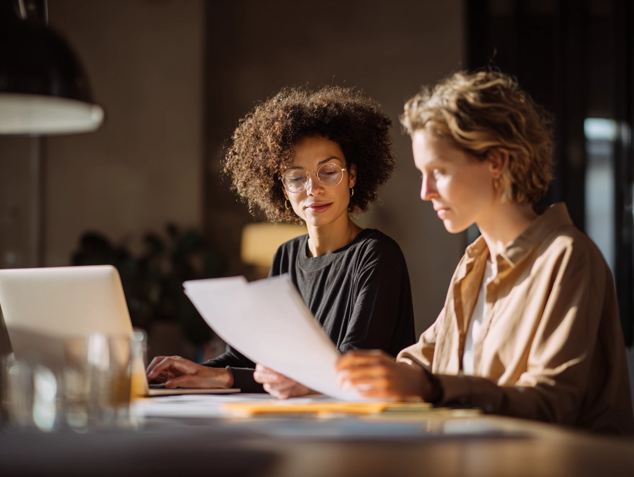 Two market researchers reviewing focus group documents and preparing fieldwork materials